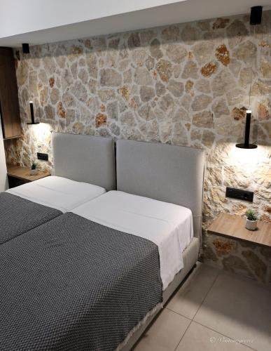 a bedroom with two beds and a stone wall at Valantina's & Mannouel Lardos Luxury Villas in Lardos