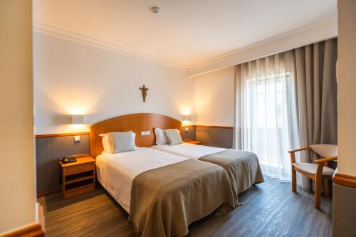a hotel room with a bed and a window at Hotel Santo Amaro - SA Hotels in Fátima