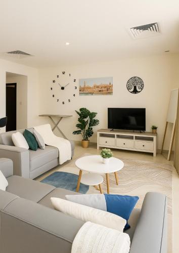 迪拜Goodwill Holidays ,Near Jumeirah Beach Residence 1的客厅配有白色家具和墙上的时钟