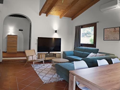 a living room with a blue couch and a flat screen tv at Villa Verde splendida villa con piscina - Stintino Sardegna in Cuile Pazzoni