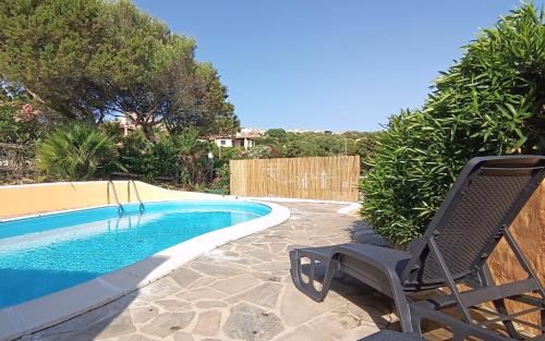 a chair sitting next to a swimming pool at Villa Verde splendida villa con piscina - Stintino Sardegna in Cuile Pazzoni