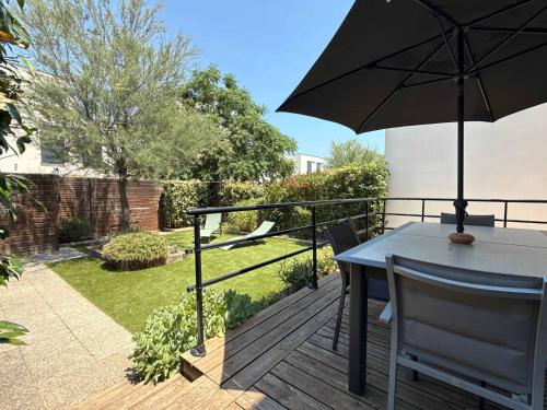 une table et des chaises avec un parasol sur une terrasse dans l'établissement Coquet pavillon avec jardin et terrasse dans une résidence à 500m de la mer, à Sérignan