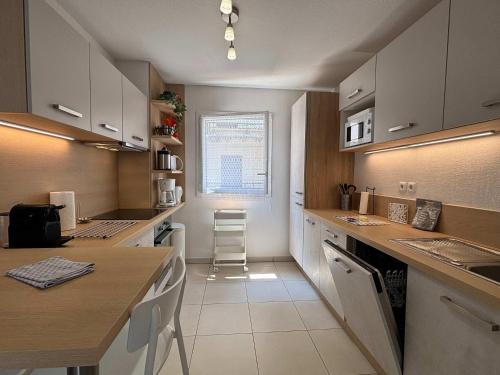 une cuisine avec des armoires blanches et un comptoir dans l'établissement Coquet pavillon avec jardin et terrasse dans une résidence à 500m de la mer, à Sérignan