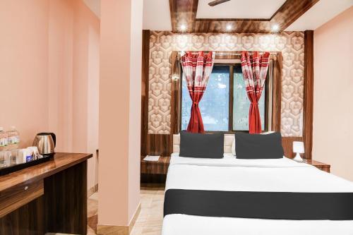 a bedroom with a bed and a window with red curtains at Super Collection O Park Circus in Kolkata