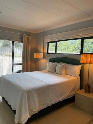 a bedroom with a large white bed with two lamps at Underberg - The Burn - Solar Powered in Underberg