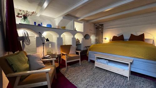 a bedroom with a bed and a couch and chairs at Huis van Marietje in Aardenburg
