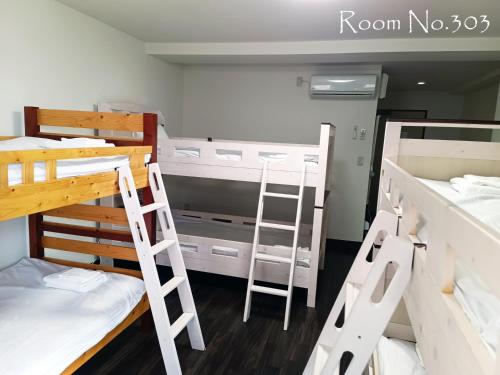a dorm room with three bunk beds and a ladder at Ace Inn Asakusa in Tokyo