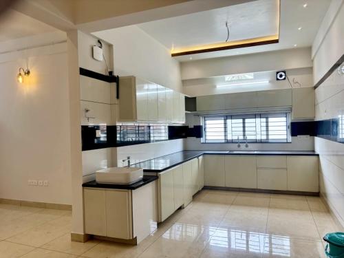 a large kitchen with white cabinets and a sink at Nestora Suites in Kozhikode