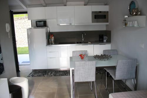 a kitchen with white cabinets and a table and chairs at Residence Il Poggio in Dorio