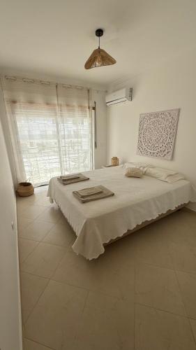 a bedroom with a large bed and a large window at BS House Praia da Lota - Casa à Beira-Mar in Vila Nova De Cacela
