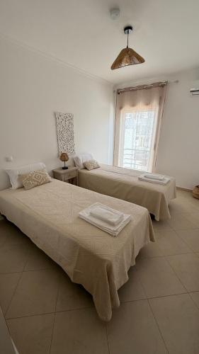 two beds in a white room with a window at BS House Praia da Lota - Casa à Beira-Mar in Vila Nova De Cacela