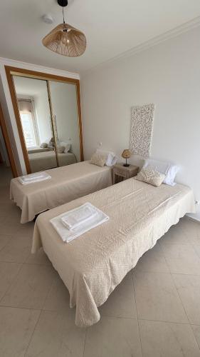 two beds in a room with a mirror at BS House Praia da Lota - Casa à Beira-Mar in Vila Nova De Cacela