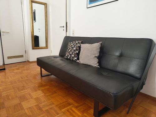 a black leather couch with two pillows on it at WHLIVING - Apartments & Studios in Konstanz in Konstanz