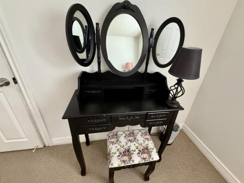 a black vanity with two mirrors and a lamp at Charming Provo Home close to BYU and Utah Lake in Provo