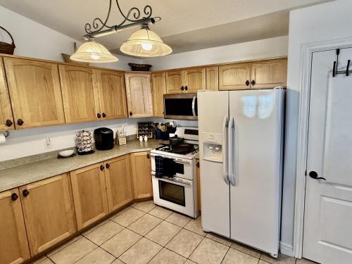 a kitchen with wooden cabinets and a white refrigerator at Charming Provo Home close to BYU and Utah Lake in Provo