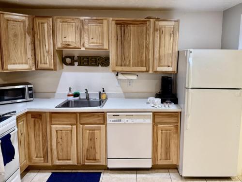 a kitchen with wooden cabinets and a white refrigerator at Charming Provo Home close to BYU and Utah Lake in Provo