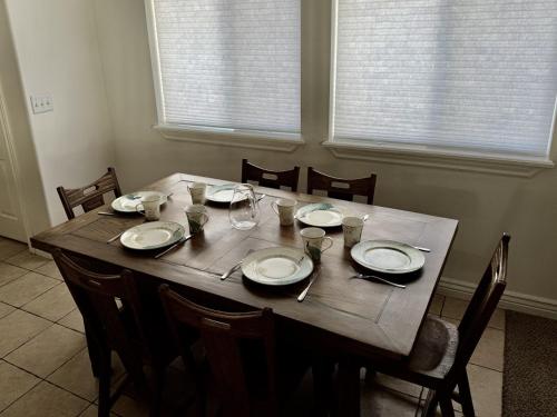 a wooden table with chairs and plates and glasses on it at Charming Provo Home close to BYU and Utah Lake in Provo