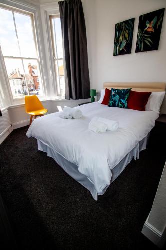 a bedroom with a large white bed with towels on it at Seahorse Guesthouse in Great Yarmouth