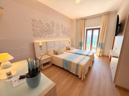 a hotel room with two beds and a desk at Hotel Dei Pini in Alghero