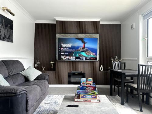 a living room with a couch and a tv on a wall at Luxury House in Glasgow in Mansewood