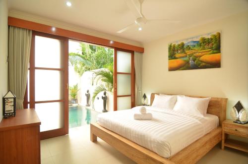 a bedroom with a bed and a view of a pool at Villa Ngetis in Sanur