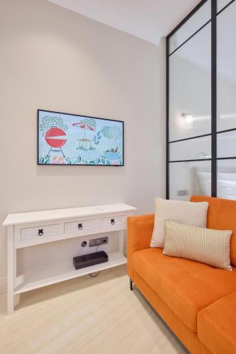 a living room with an orange couch and a tv at Aparthotel 9 ALBERTI Nice Centre in Nice