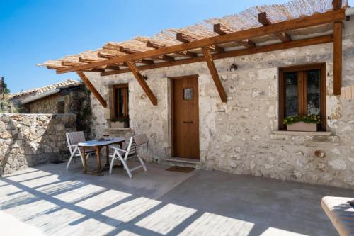 a patio of a stone house with a table and chairs at Anyfantata in Sívros