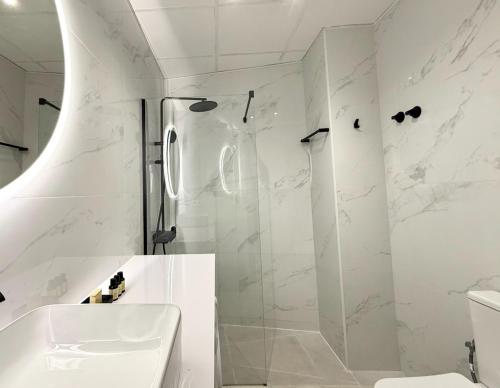 a white bathroom with a shower and a sink at iloftmalaga Ático Pozos Dulces in Málaga