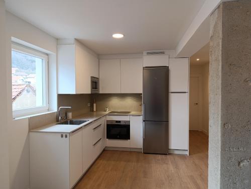 a kitchen with white cabinets and a stainless steel refrigerator at Apartamento EGUZKILORE Izaba-Isaba in Isaba