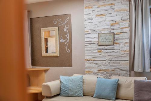 a living room with a couch and a stone wall at Wia Dahoam Appartement in Völs
