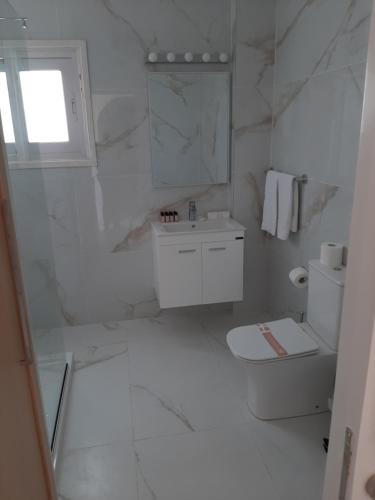 a white bathroom with a toilet and a sink at Protaras Plaza Hotel in Protaras