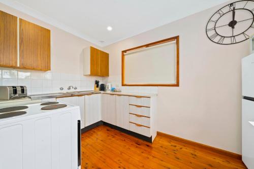 een keuken met witte apparatuur en een klok aan de muur bij Godfrey's Cottage in Blackheath