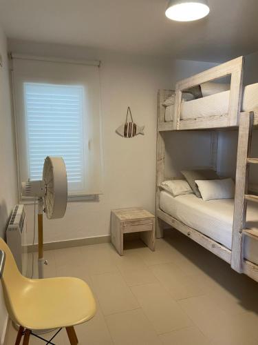 a bedroom with two bunk beds and a yellow chair at BINIPARADISE Villas in Binibeca