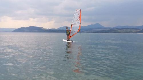 a man standing on a surfboard with a sail on the water at Apartman Marienka in Liptovský Trnovec