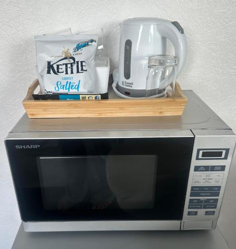 a microwave with a coffee pot on top of it at fAiRy DeLL Guesthouse, with cozy lockable rooms, tv, tea tray with choccies, free wifi and parking, 24hr check in, COA, all are welcome in Bradford