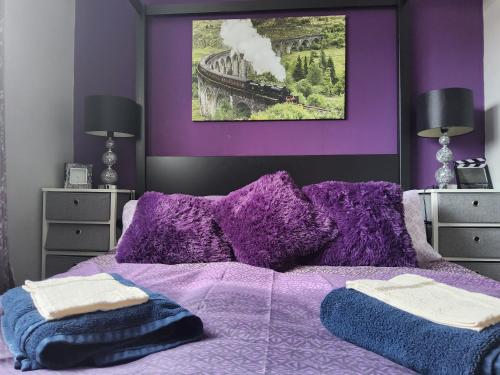 a purple bed with a purple wall with a train picture at Gadsby manor in Drumchapel