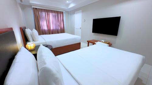 a hotel room with two beds and a flat screen tv at Whiterock Beach Hotel and Waterpark in Subic