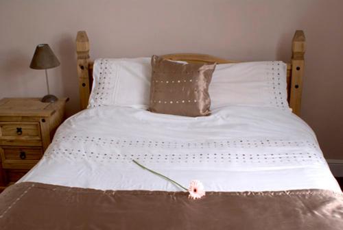 a white bed with a pink flower on it at George & Dragon in Coleshill