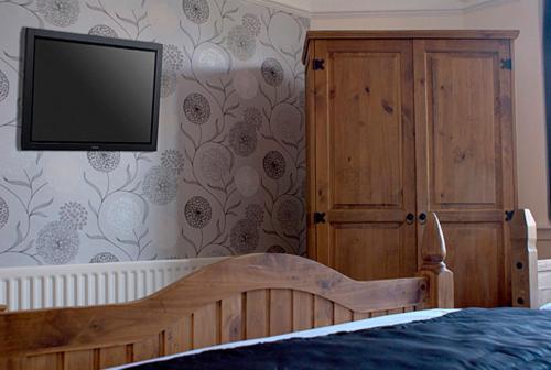 科爾斯希爾的住宿－喬治與龍酒店，卧室配有一张床,墙上配有电视。