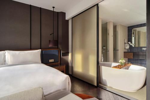 a bedroom with a bed and a tub and a television at InterContinental Bangkok Sukhumvit by IHG in Bangkok
