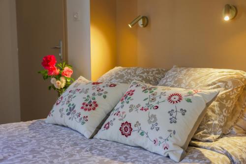 a bed with two pillows and a vase with flowers at Clos Ceres in Viré