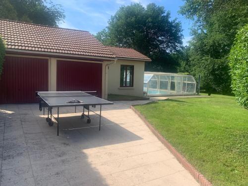 a ping pong table in a yard with a greenhouse at La PISCINE in Saint-Vallier