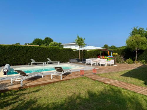 a swimming pool with chairs and a table and a table at Arès, Villa Mapouchet, piscine in Arès