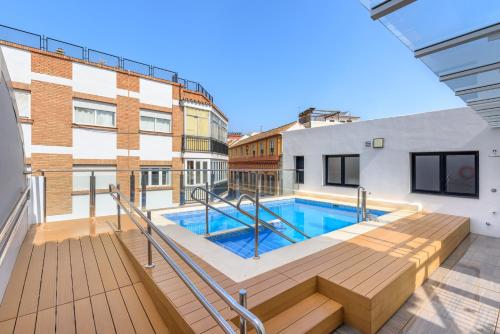 a swimming pool with a wooden deck and a building at Exe Málaga Museos in Málaga
