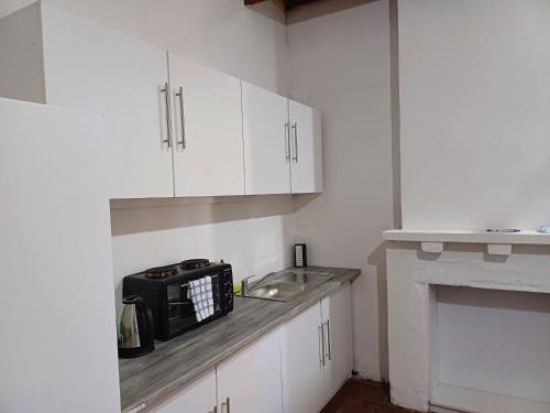 a kitchen with white cabinets and a microwave on a counter at 19 on Smit in Piet Retief