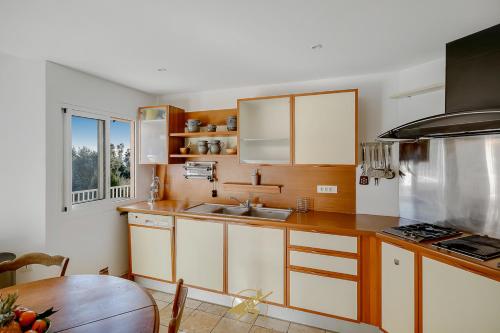 a kitchen with white cabinets and a sink and a table at Maison de la Pointe - 4 etoiles - Vue mer - Piscine - Rayol Canadel in Rayol-Canadel-sur-Mer