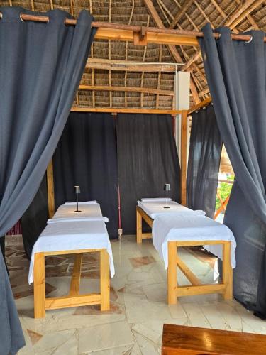 two beds in a room with blue curtains at Smile Boutique Beach hotel in Nungwi