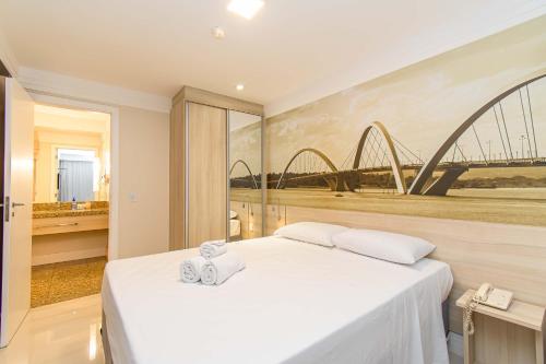 a bedroom with a white bed with a painting of a bridge at BSB STAY Torre Flats Particulares - Mercure Líder in Brasilia