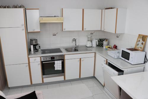 a kitchen with white cabinets and a sink and a microwave at Holiday Home Peaceful Retreat in Visoko