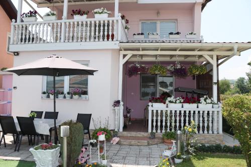 a pink house with a balcony and a table with an umbrella at Holiday Home Peaceful Retreat in Visoko